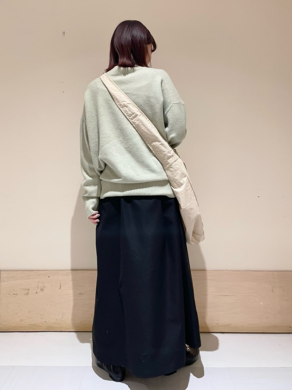 グリーン系のニット/セーター、ブラック系のスカート、グレー系のショルダーバッグを着用したレディースの冬コーディネートの7枚目の写真