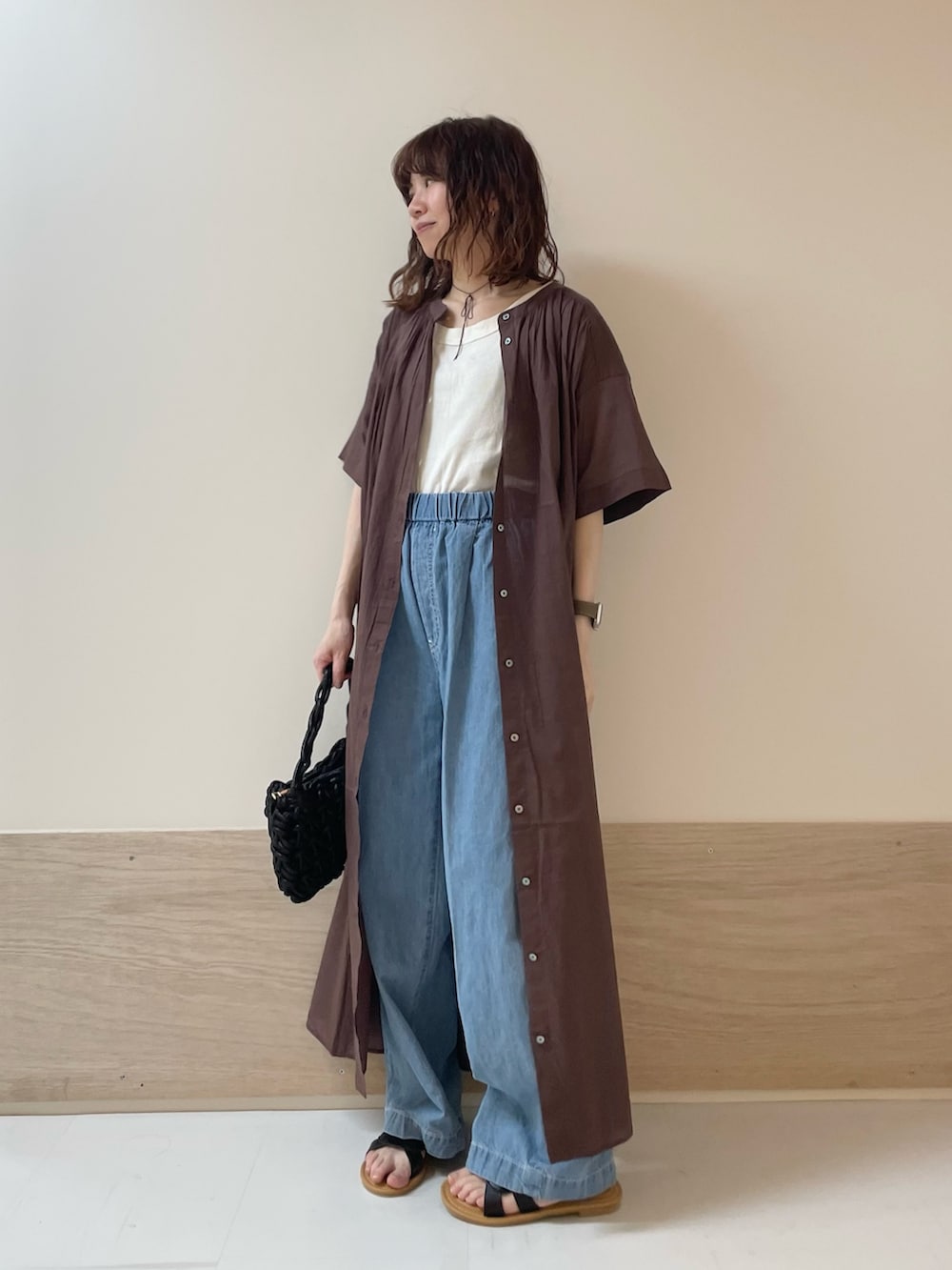 ブルー系のデニムパンツ、ブラック系のサンダル、ブラウン系のワンピースを着用したレディースの春コーディネートの5枚目の写真