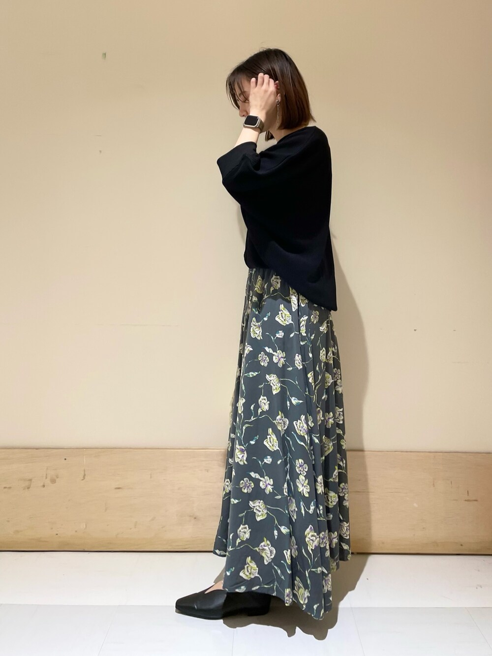 グレー系のスカート、ホワイト系のショルダーバッグ、ブラック系のパンプスを着用したレディースの秋コーディネートの4枚目の写真