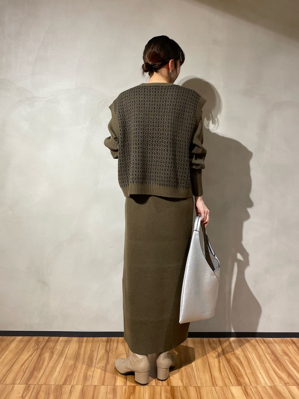 シルバー系のトートバッグ、グリーン系のワンピース、グレー系のブーツを着用したレディースの秋コーディネートの3枚目の写真