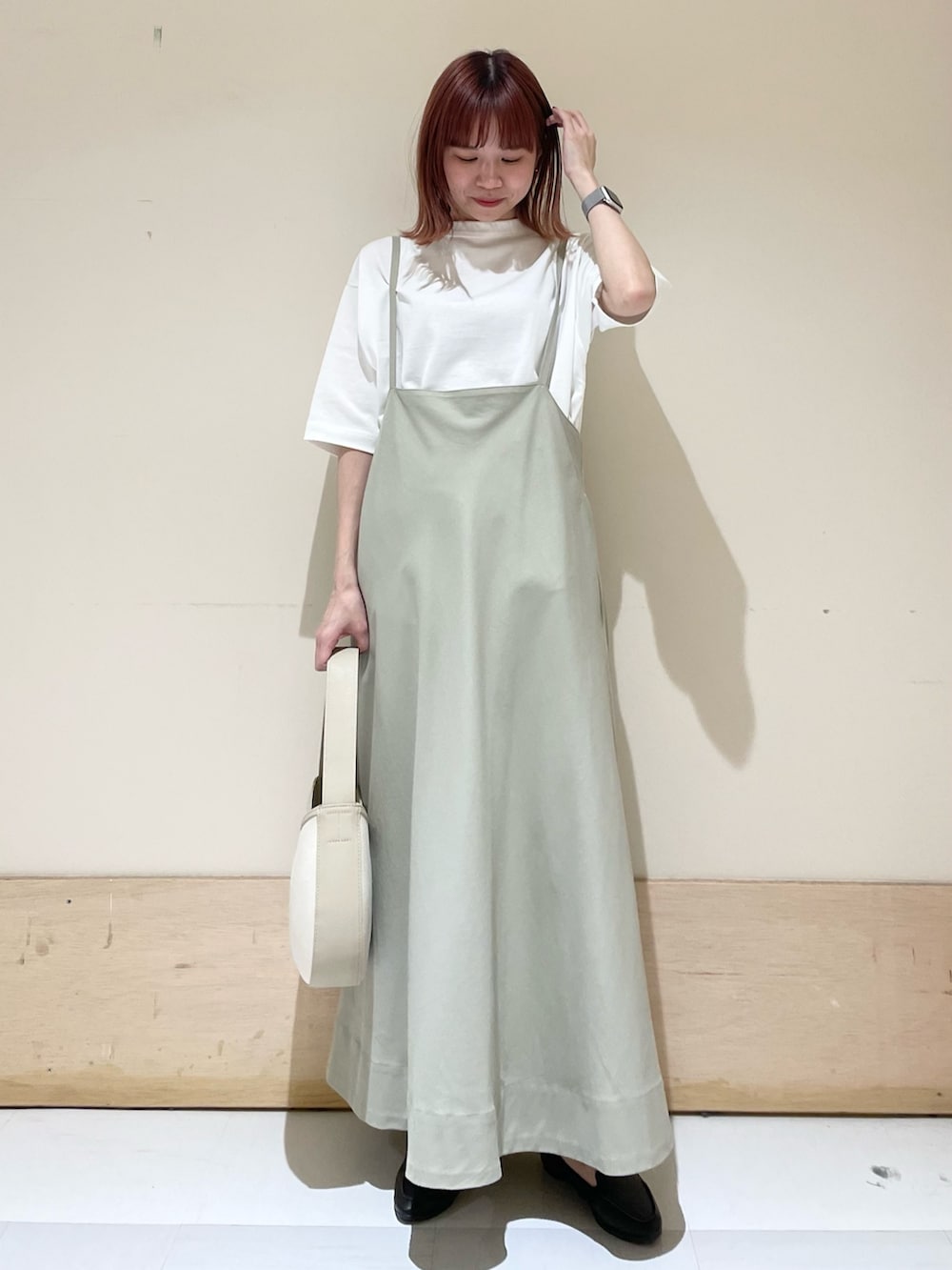 ベージュ系のハンドバッグ、ブラック系のスリッポン、ホワイト系のTシャツ/カットソーを着用したレディースの春コーディネートの2枚目の写真