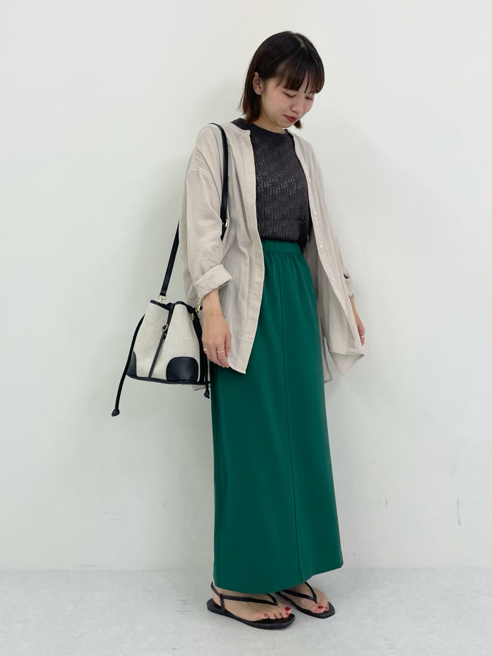 ブラック系のサンダル、グリーン系のスカート、グレー系のニット/セーターを着用したレディースの夏コーディネートの2枚目の写真