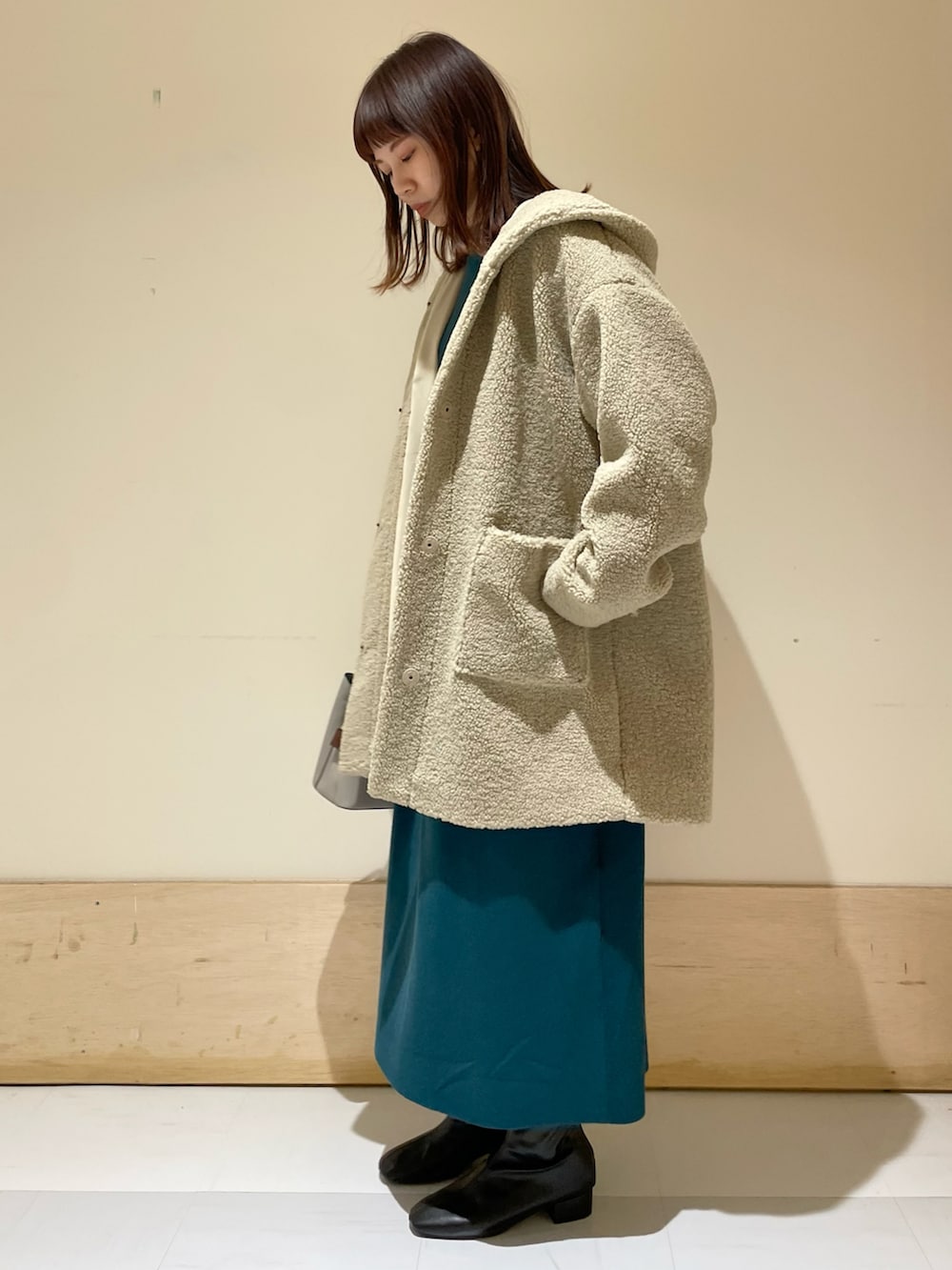 ベージュ系のその他アウター、ブルー系のワンピース、ブラック系のブーツを着用したレディースの冬コーディネートの2枚目の写真