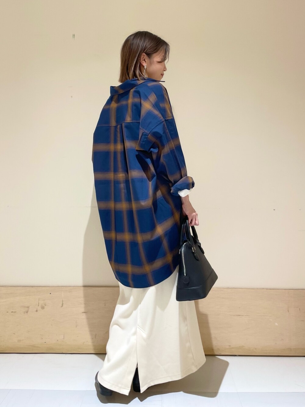 ベージュ系のスカート、ブラック系のパンプス、ブラック系のショルダーバッグを着用したレディースの秋コーディネートの7枚目の写真