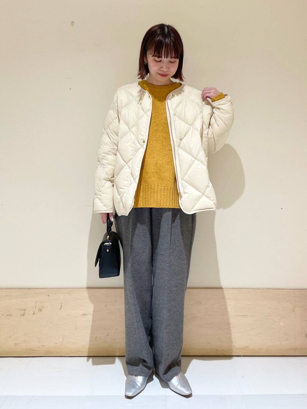 イエロー系のニット/セーター、グレー系のその他パンツ、ブラック系のショルダーバッグを着用したレディースの秋コーディネートの3枚目の写真