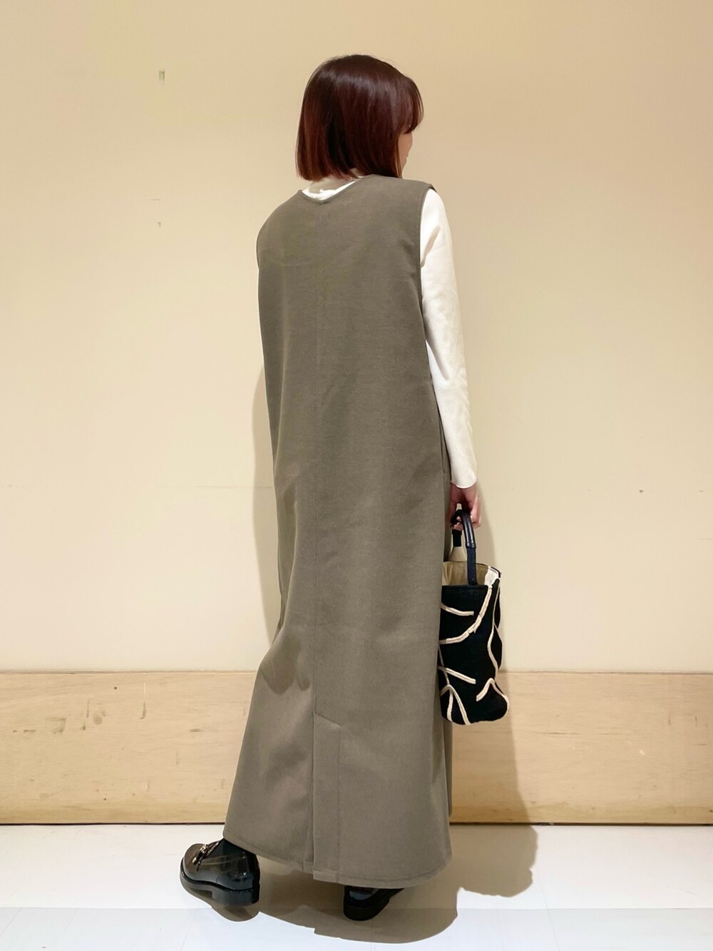 ブラウン系のワンピース、ホワイト系のTシャツ/カットソー、ブラック系のショルダーバッグを着用したレディースの秋コーディネートの7枚目の写真