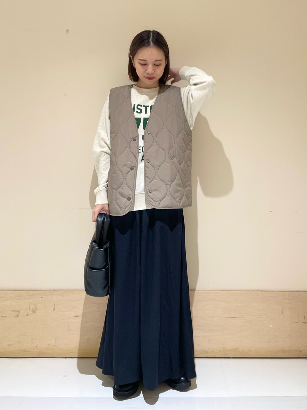 ブラック系のスカート、ブラック系のブーツ、ブラウン系のダウンベストを着用したレディースの秋コーディネートの3枚目の写真