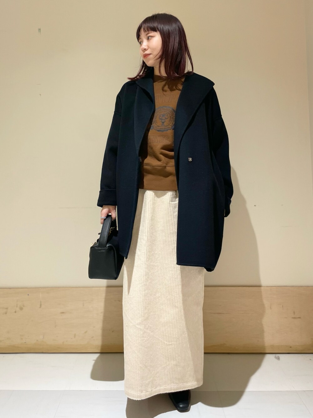 ブラウン系のスウェット、ブラック系のその他アウター、ホワイト系のスカートを着用したレディースの冬コーディネートの2枚目の写真