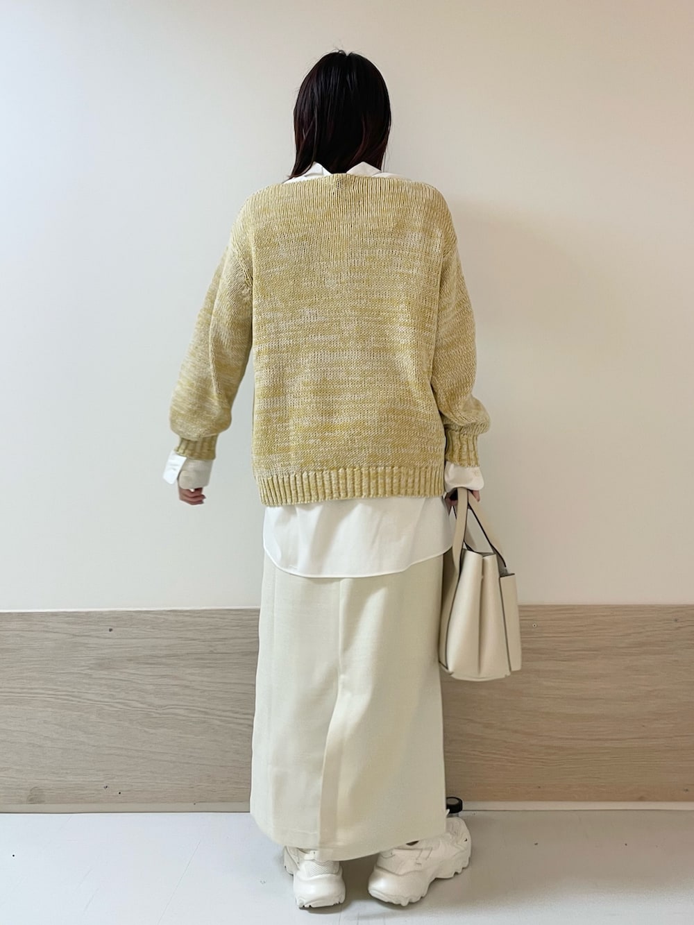 イエロー系のニット/セーター、ホワイト系のシャツ/ブラウス、ホワイト系のスカートを着用したレディースの春コーディネートの6枚目の写真