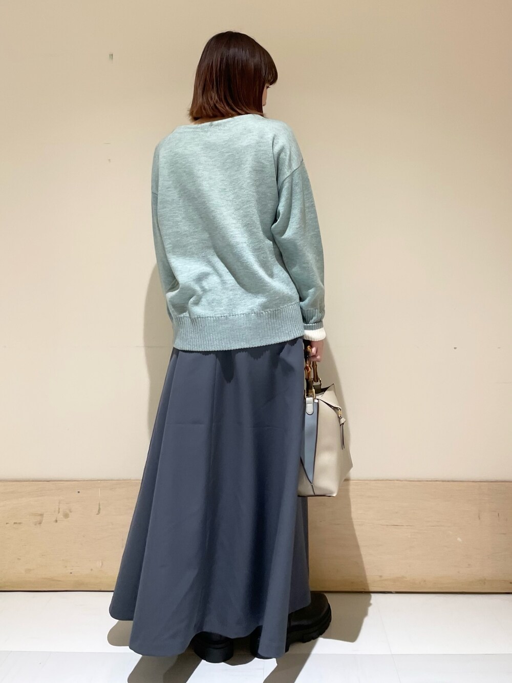 グレー系のスカート、グリーン系のニット/セーターを着用したレディースの冬コーディネートの6枚目の写真