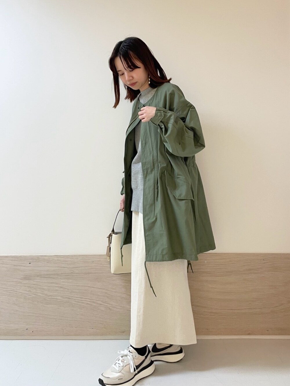 グリーン系のモッズコート、グレー系のTシャツ/カットソー、ホワイト系のスカートを着用したレディースの春コーディネートの4枚目の写真