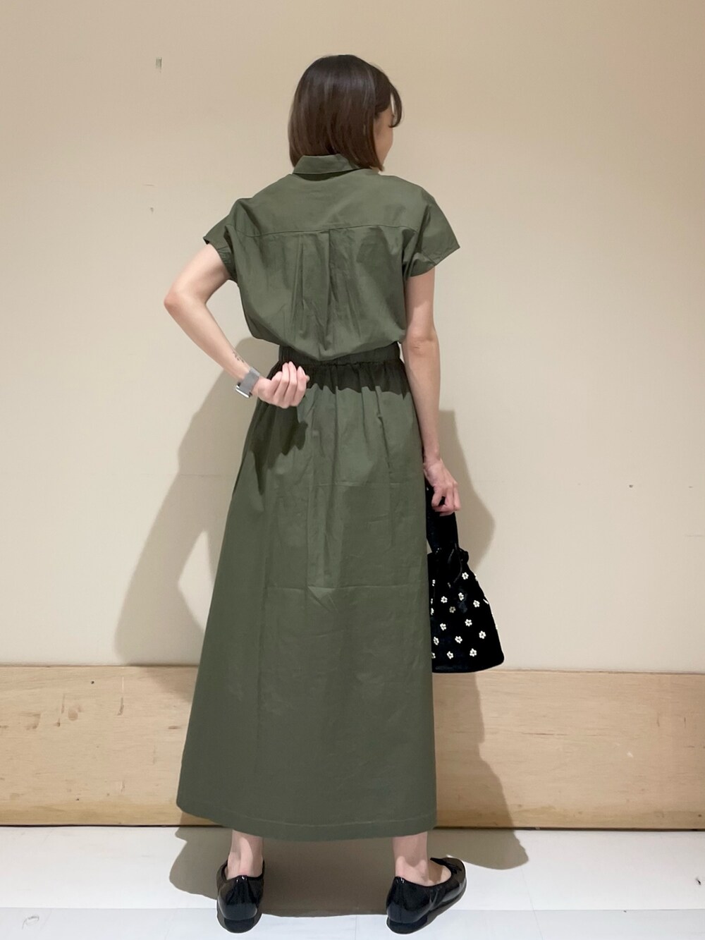 ブラック系のパンプス、ベージュ系のハンドバッグ、グリーン系のワンピースを着用したレディースの夏コーディネートの6枚目の写真