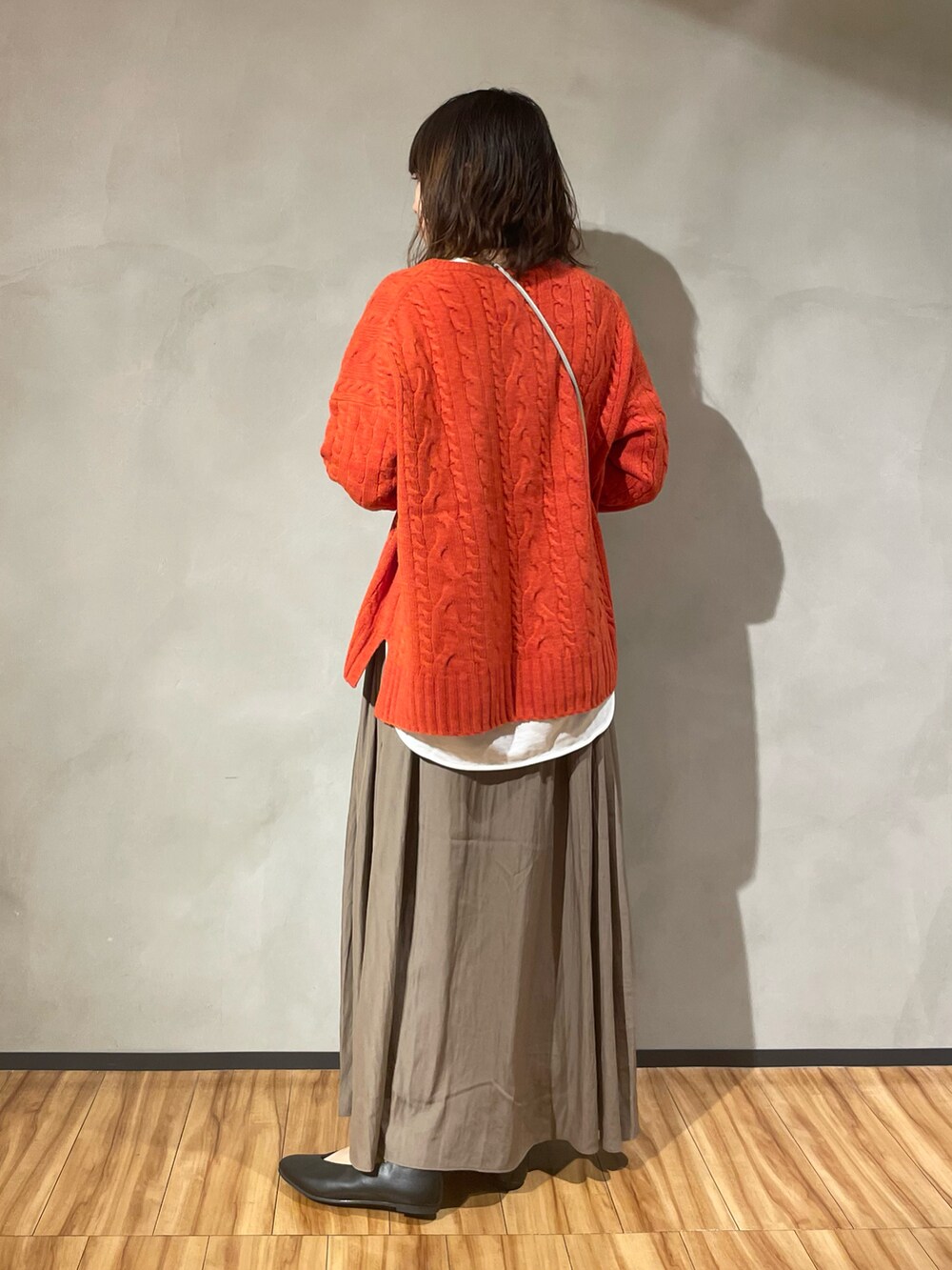 オレンジ系のニット/セーター、ブラウン系のスカート、ブラック系のパンプスを着用したレディースの秋コーディネートの3枚目の写真