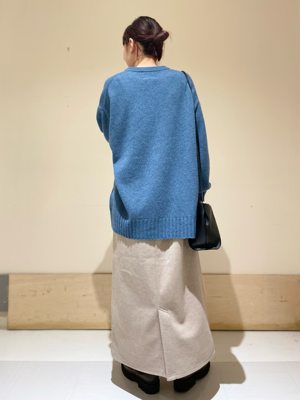 ブルー系のニット/セーター、ベージュ系のスカート、ブラック系のショルダーバッグを着用したレディースの冬コーディネートの4枚目の写真