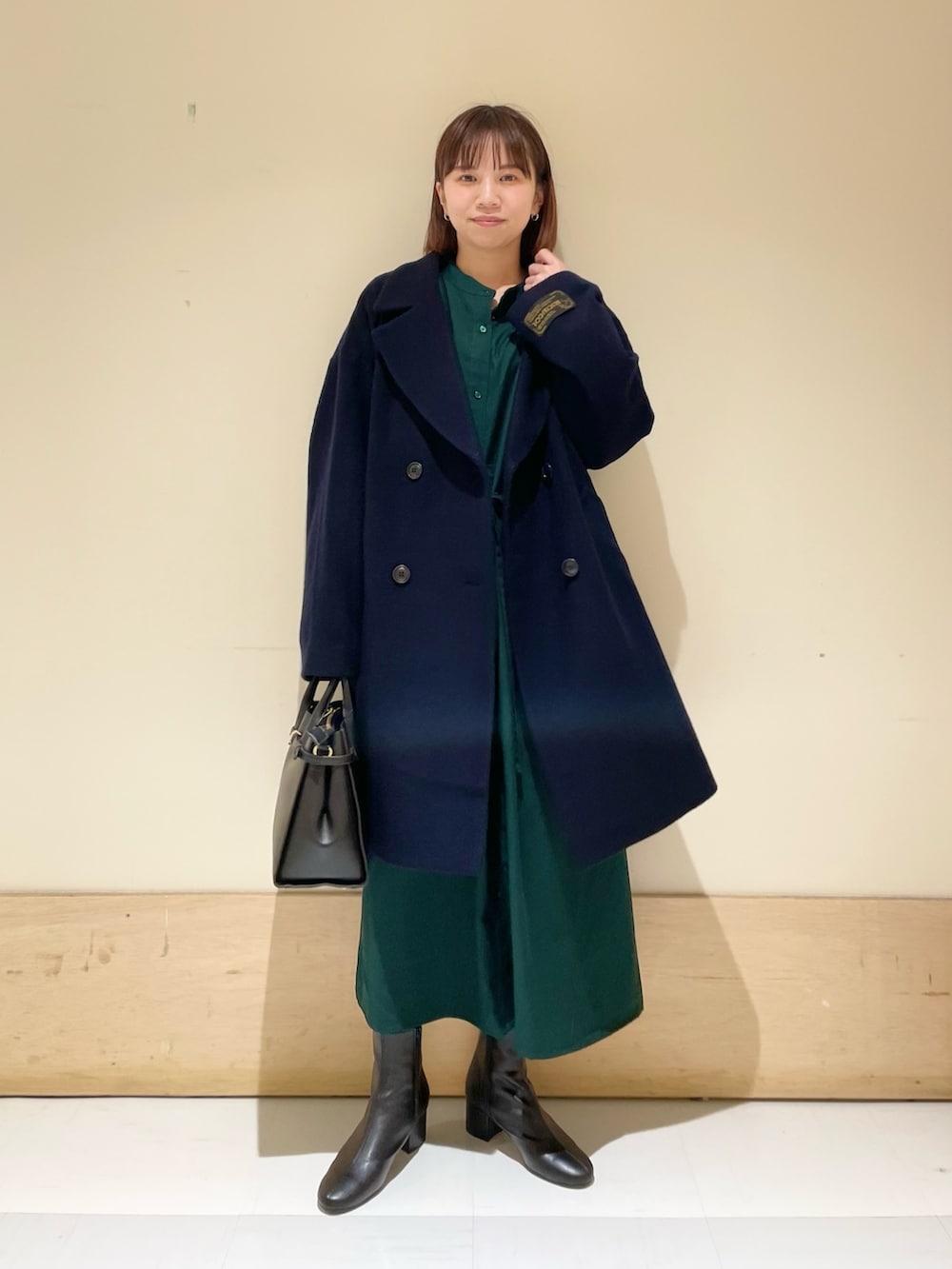 グリーン系のワンピース、ブルー系のピーコート、ブラック系のブーツを着用したレディースの冬コーディネートの2枚目の写真