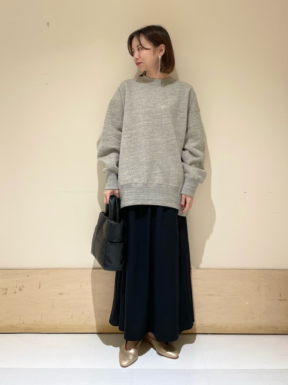 ブラック系のトートバッグ、ゴールド系のパンプス、グレー系のスウェットを着用したレディースの秋コーディネートの2枚目の写真