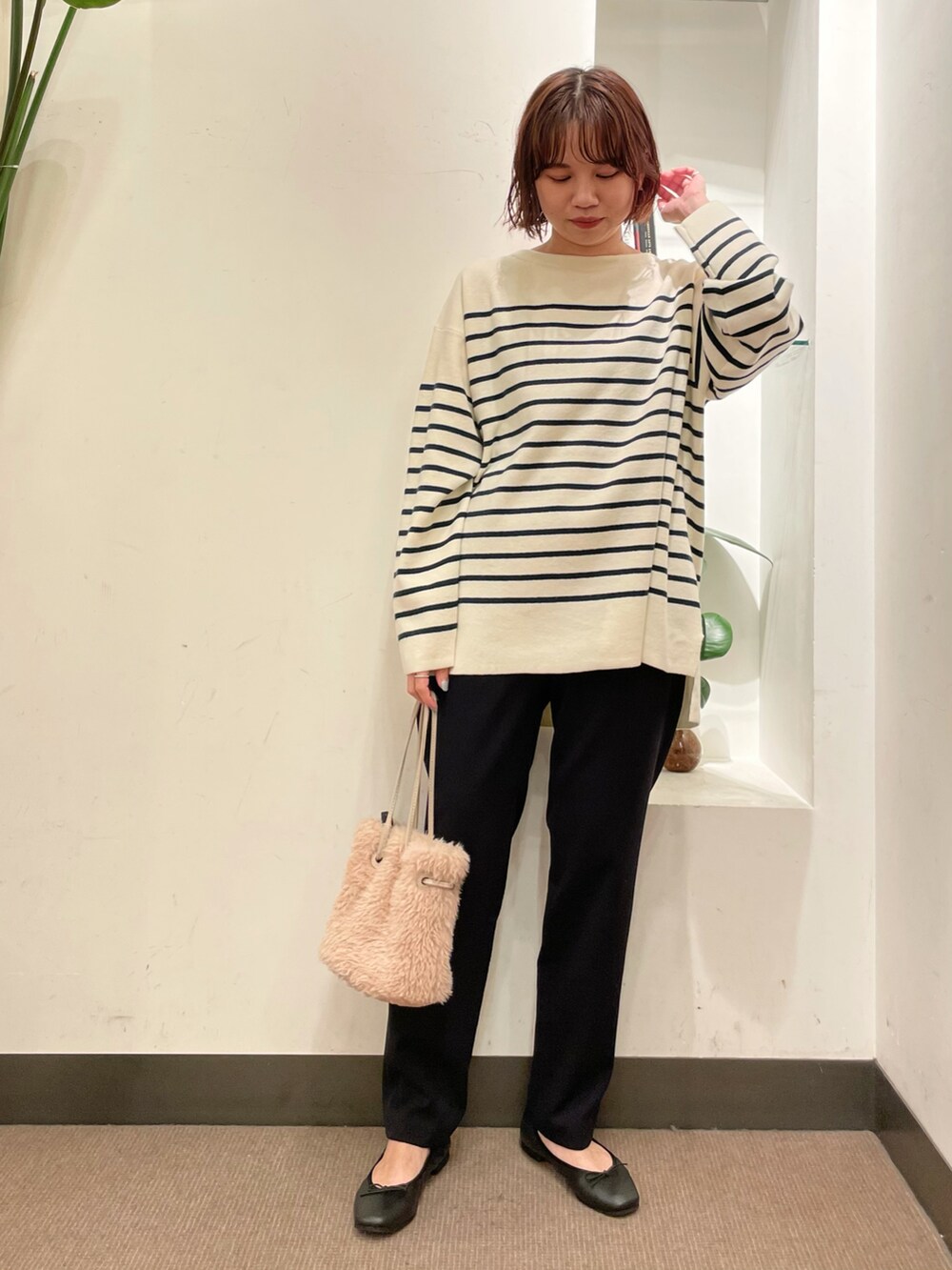 グリーン系のニット/セーター、ブラック系のその他パンツ、ベージュ系のハンドバッグを着用したレディースの冬コーディネートの2枚目の写真