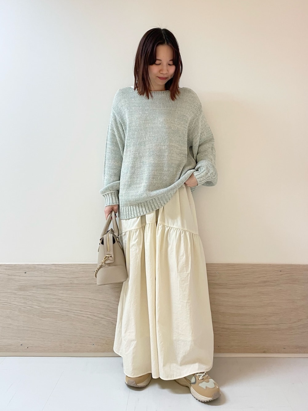 グリーン系のニット/セーター、ホワイト系のスカート、ベージュ系のスニーカーを着用したレディースの春コーディネートの3枚目の写真