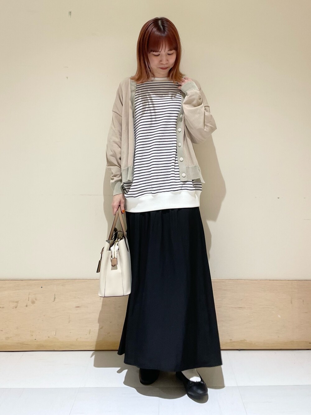 ブラック系のスカート、ホワイト系のTシャツ/カットソー、ベージュ系のカーディガン/ボレロを着用したレディースの春コーディネートの3枚目の写真