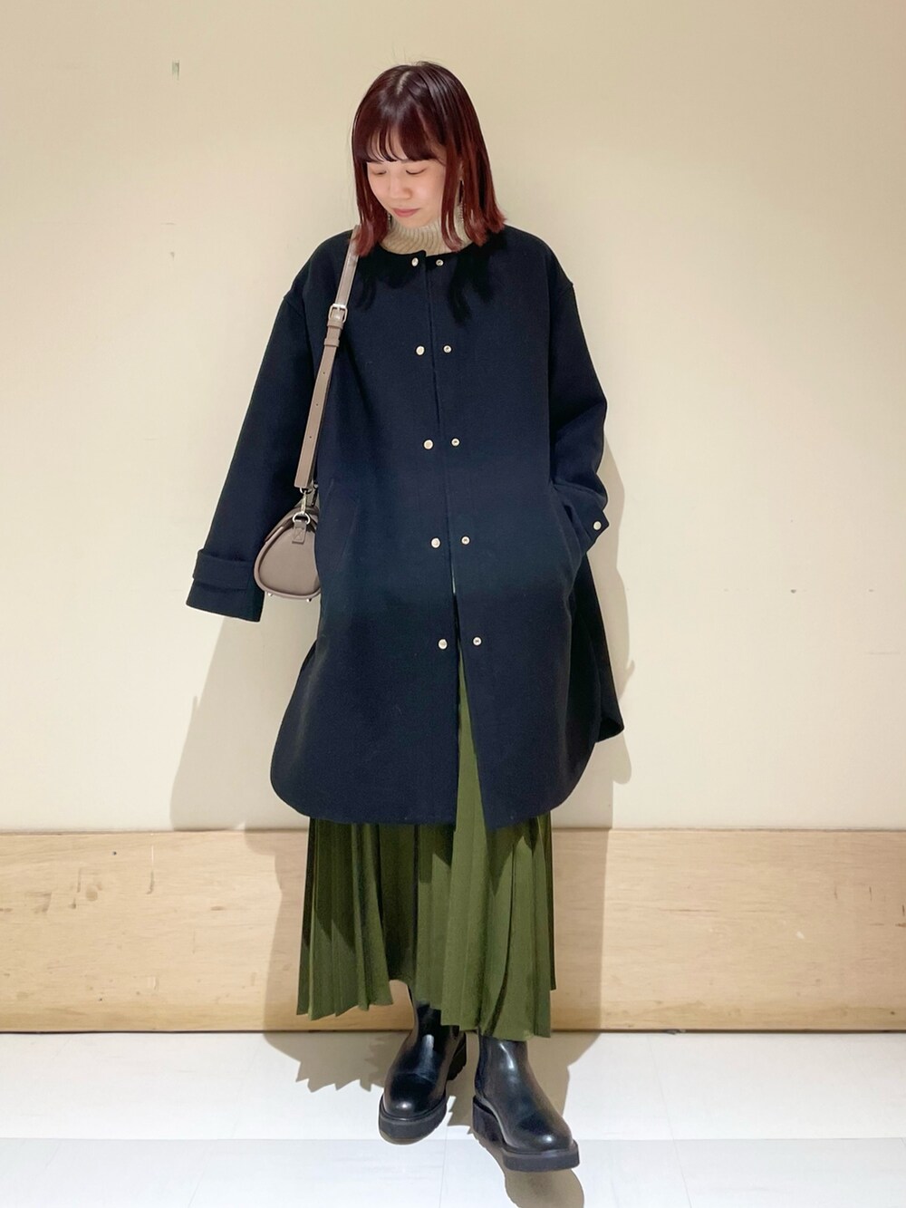 ブラック系のその他アウター、ブラック系のブーツ、グリーン系のスカートを着用したレディースの冬コーディネートの2枚目の写真