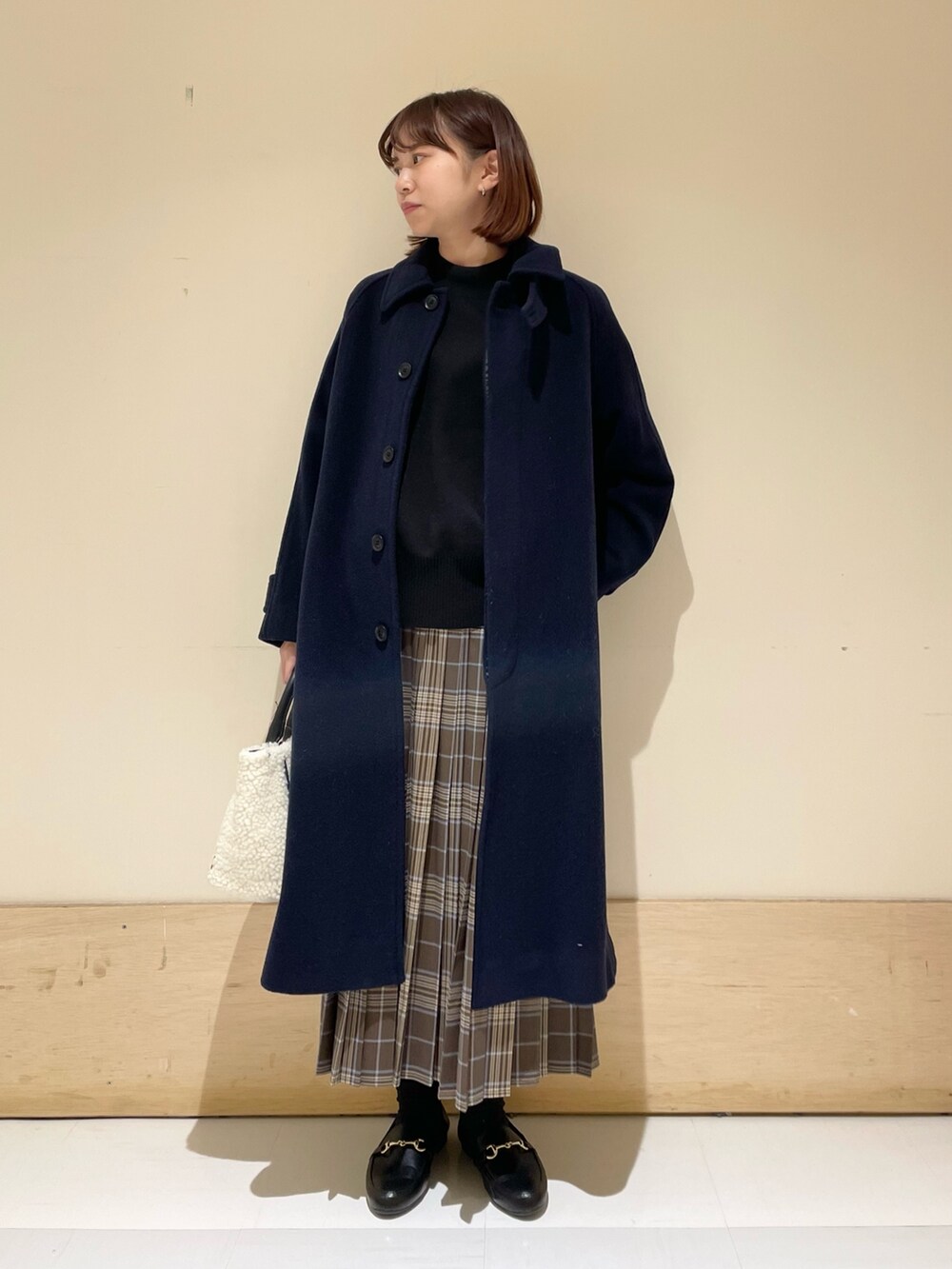 ブラック系のニット/セーター、ホワイト系のショルダーバッグ、ブラウン系のスカートを着用したレディースの冬コーディネートの3枚目の写真