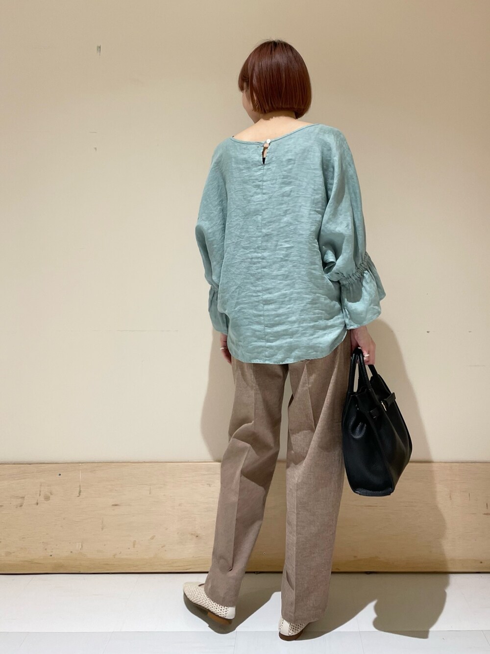 グリーン系のシャツ/ブラウス、ブラック系のトートバッグ、ホワイト系のバレエシューズを着用したレディースの春コーディネートの7枚目の写真