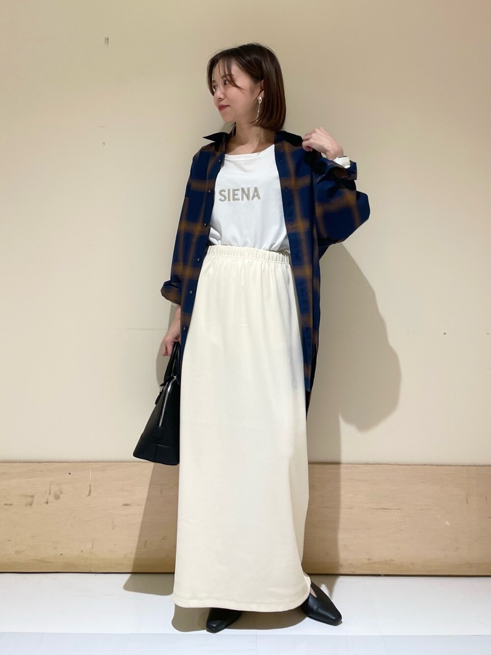 ベージュ系のスカート、ブラック系のパンプス、ブラック系のショルダーバッグを着用したレディースの秋コーディネートの2枚目の写真