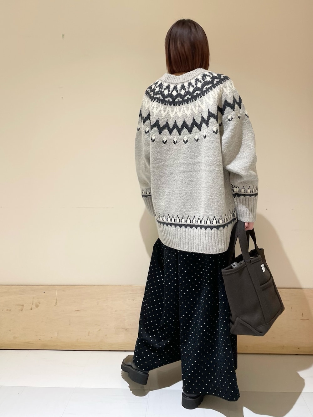 グレー系のニット/セーター、ブラック系のブーツ、ブラウン系のトートバッグを着用したレディースの秋コーディネートの7枚目の写真