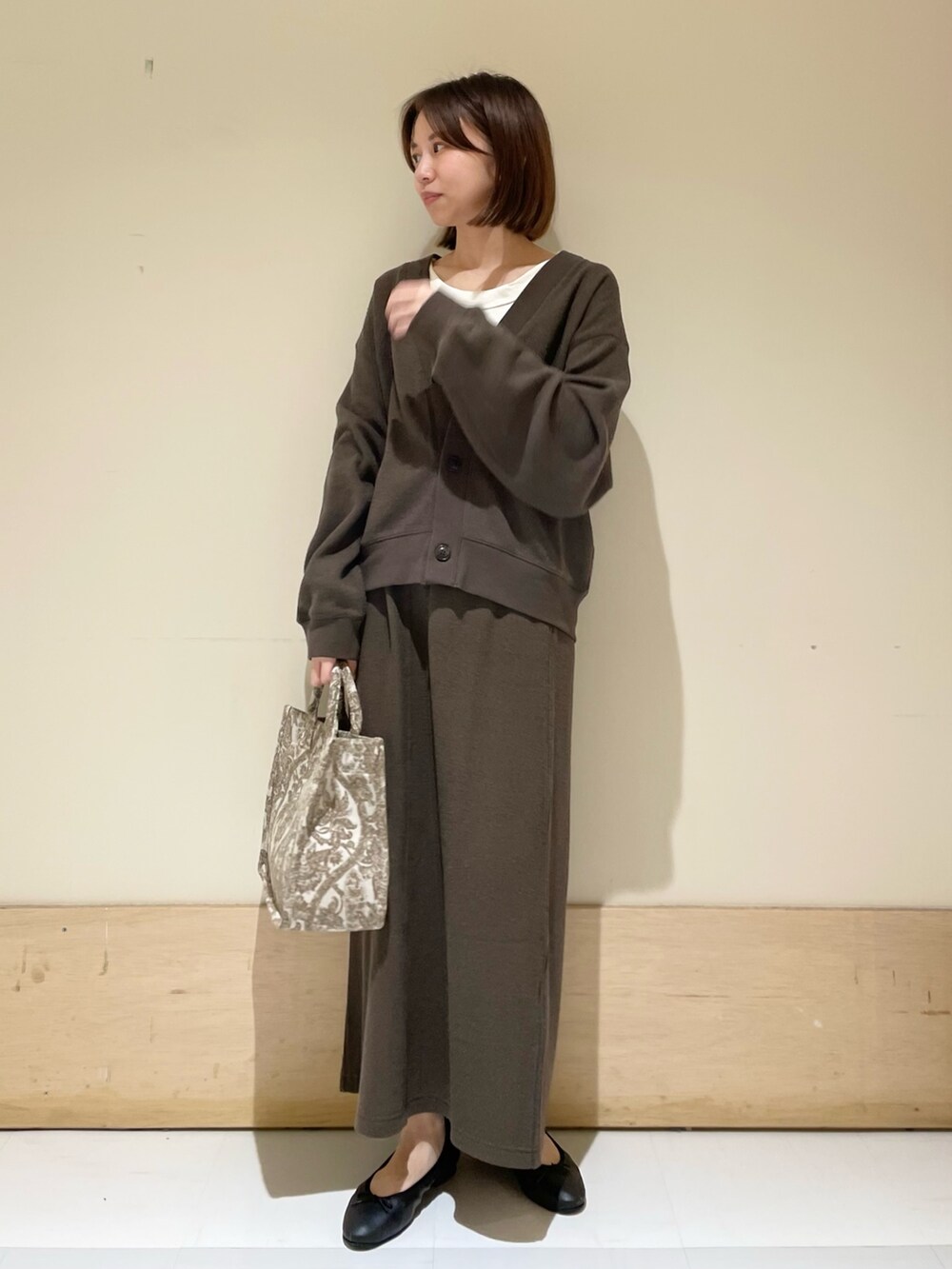 ベージュ系のトートバッグ、ホワイト系のタンクトップ、グレー系のカーディガン/ボレロを着用したレディースの秋コーディネートの3枚目の写真