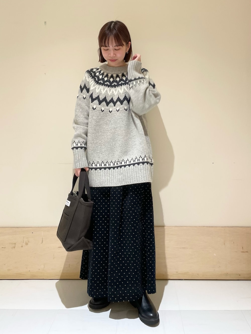 グレー系のニット/セーター、ブラック系のブーツ、ブラウン系のトートバッグを着用したレディースの秋コーディネートの3枚目の写真