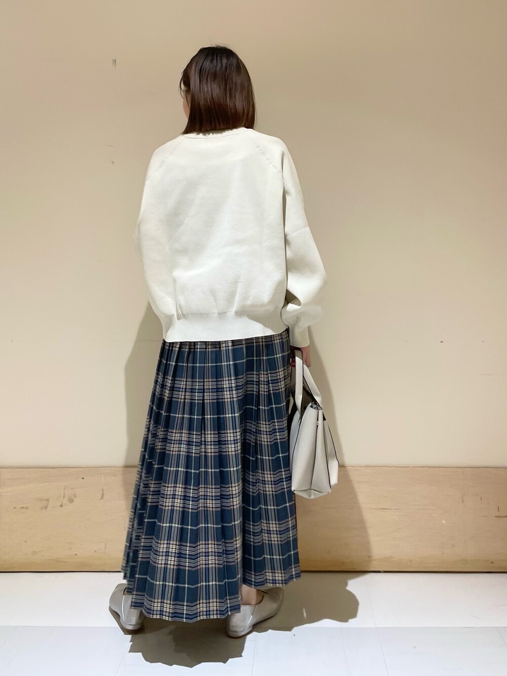 ホワイト系のニット/セーター、グレー系のトートバッグ、ブルー系のスカートを着用したレディースの秋コーディネートの5枚目の写真