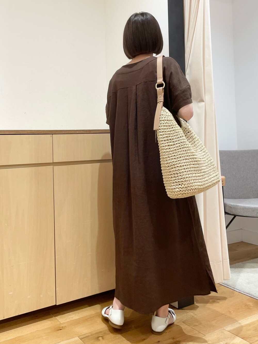 ホワイト系のサンダル、ベージュ系のかごバッグ、ブラウン系のワンピースを着用したレディースの夏コーディネートの5枚目の写真