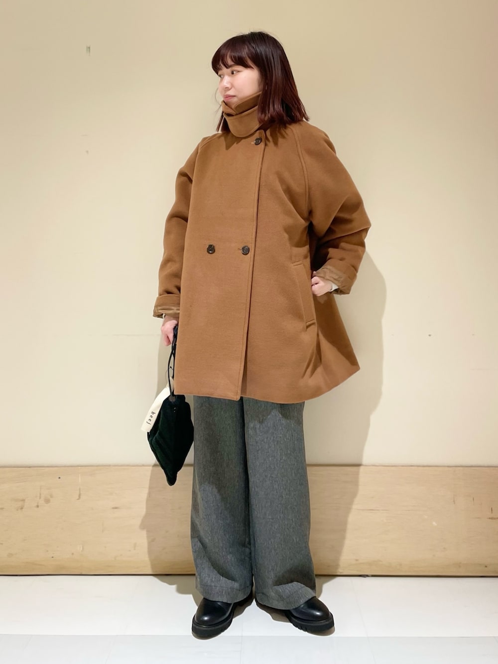 イエロー系のピーコート、グレー系のTシャツ/カットソー、ブラック系のハンドバッグを着用したレディースの冬コーディネートの3枚目の写真