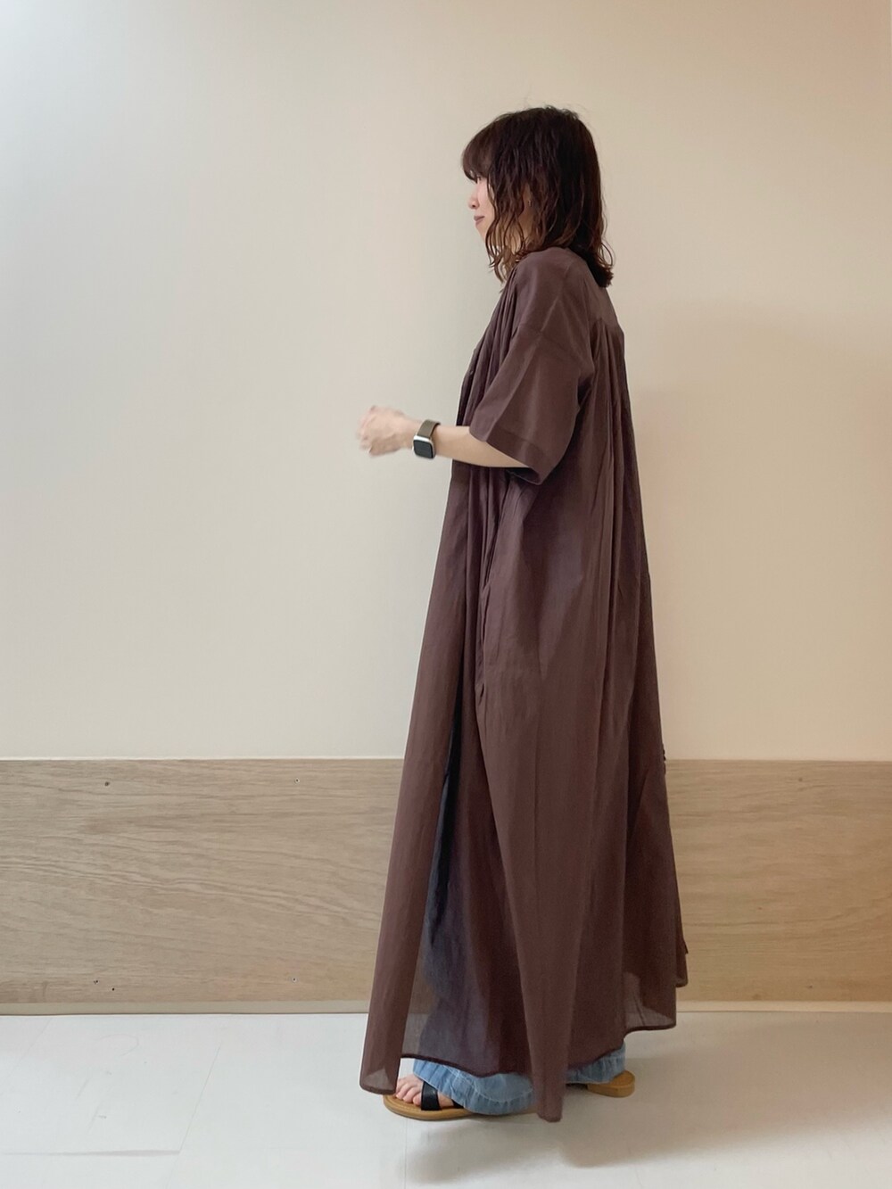 ブルー系のデニムパンツ、ブラック系のサンダル、ブラウン系のワンピースを着用したレディースの春コーディネートの6枚目の写真