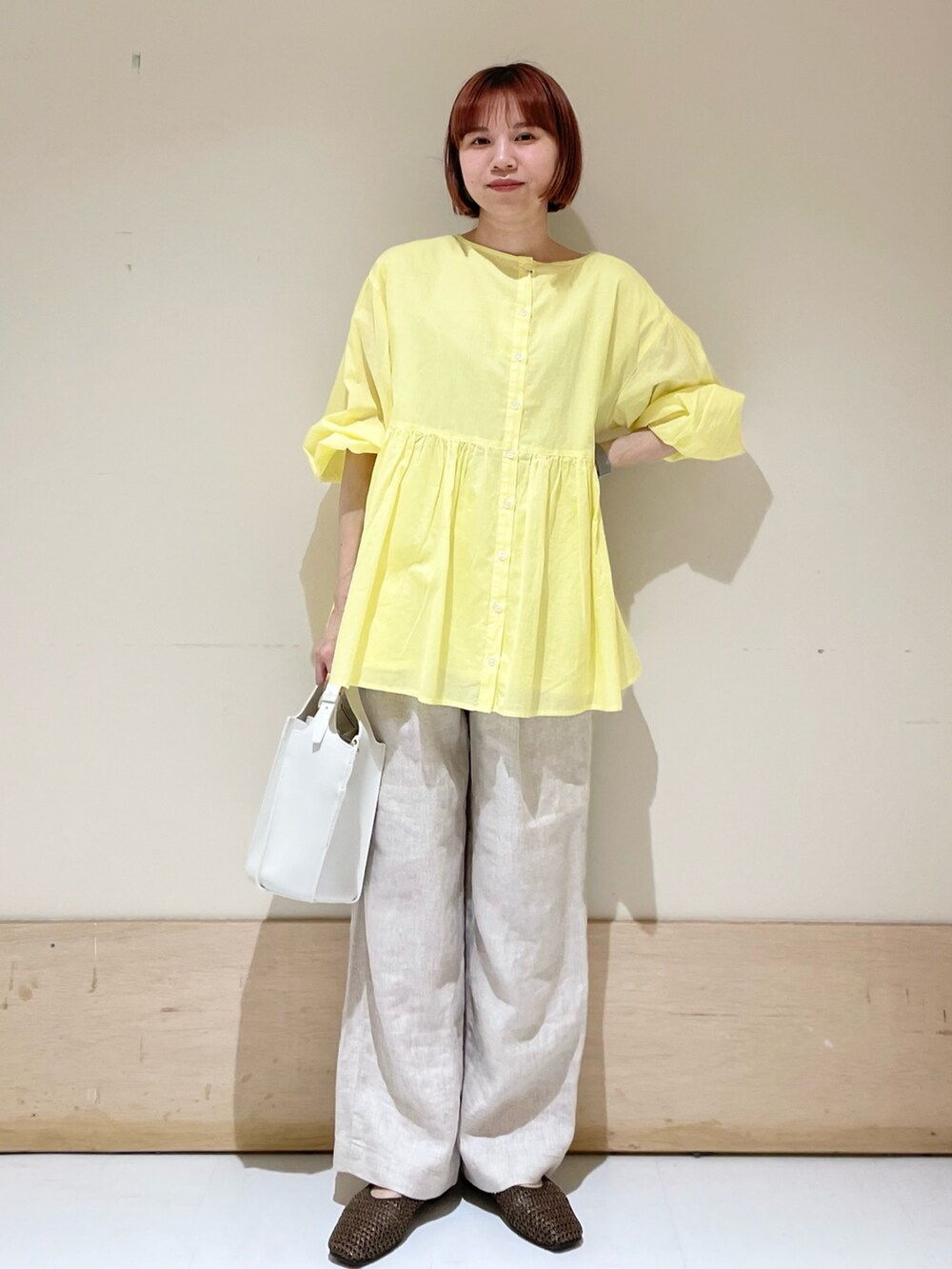 ベージュ系のその他パンツ、イエロー系のシャツ/ブラウス、ホワイト系のトートバッグを着用したレディースの春コーディネートの2枚目の写真