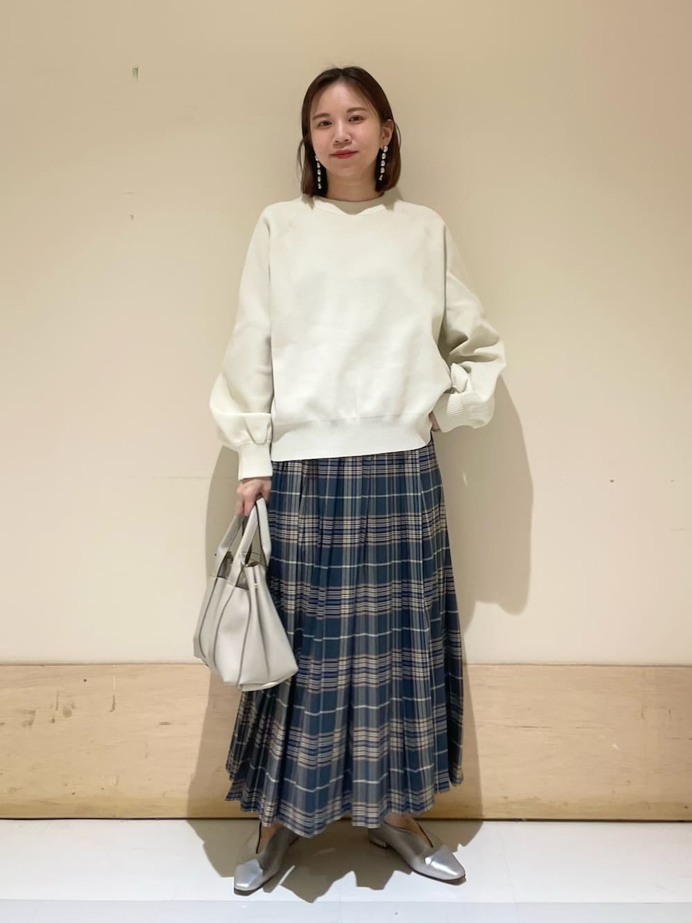 ホワイト系のニット/セーター、グレー系のトートバッグ、ブルー系のスカートを着用したレディースの秋コーディネートの3枚目の写真