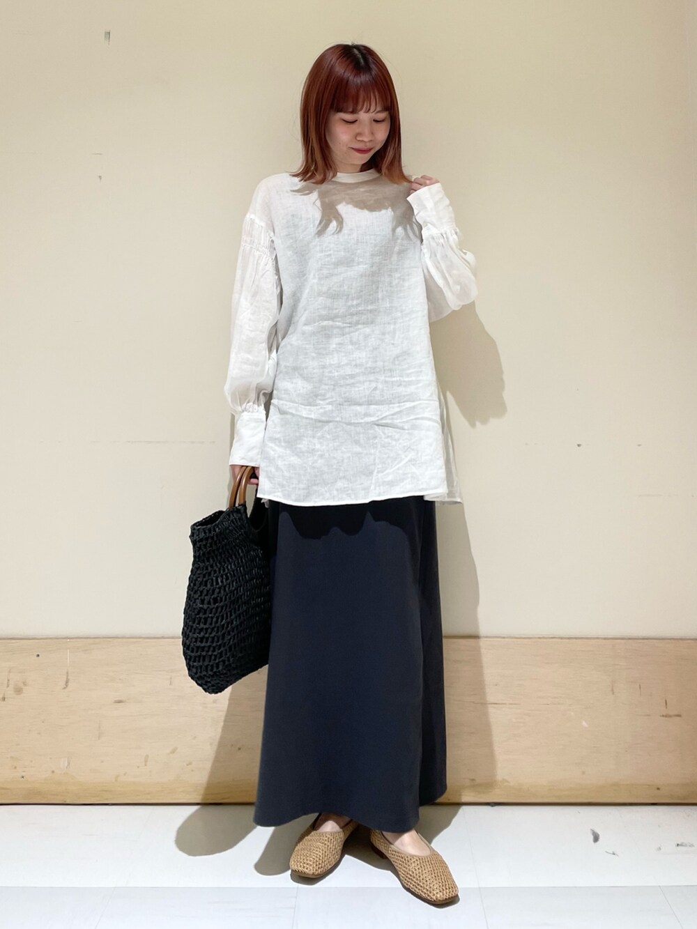 ホワイト系のシャツ/ブラウス、グレー系のスカート、ブラック系のかごバッグを着用したレディースの春コーディネートの2枚目の写真