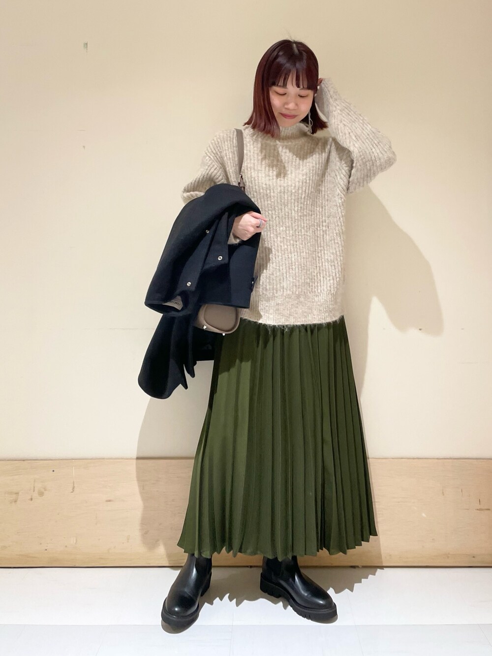 ブラック系のその他アウター、ブラック系のブーツ、グリーン系のスカートを着用したレディースの冬コーディネートの6枚目の写真