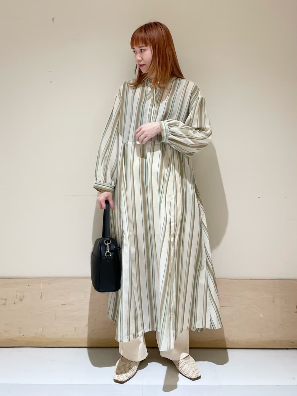 グリーン系のワンピース、ホワイト系のパンプス、ブラック系のショルダーバッグを着用したレディースの春コーディネートの2枚目の写真