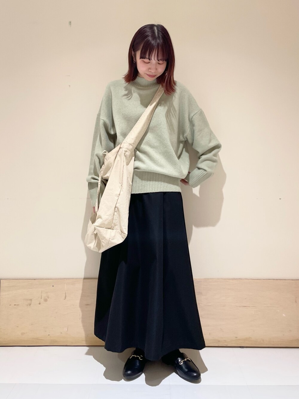 グリーン系のニット/セーター、ブラック系のスカート、グレー系のショルダーバッグを着用したレディースの冬コーディネートの3枚目の写真