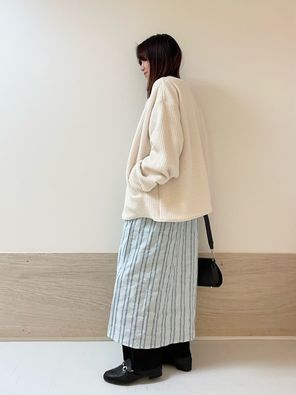 ブラック系のショルダーバッグ、ホワイト系のノーカラージャケット、ブルー系のワンピースを着用したレディースの春コーディネートの4枚目の写真