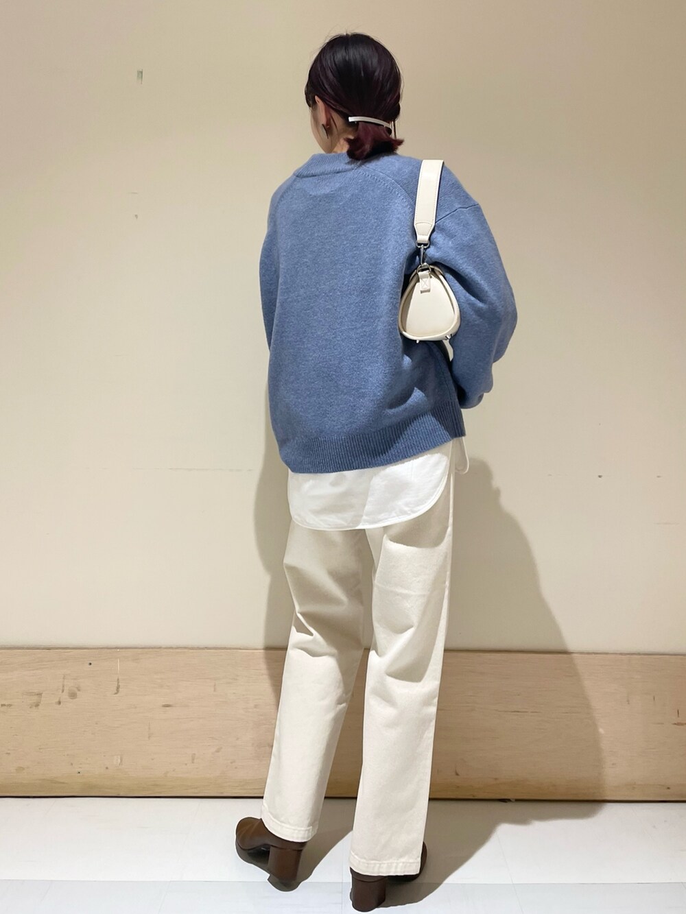 ベージュ系のデニムパンツ、ブルー系のニット/セーター、ホワイト系のショルダーバッグを着用したレディースの冬コーディネートの6枚目の写真