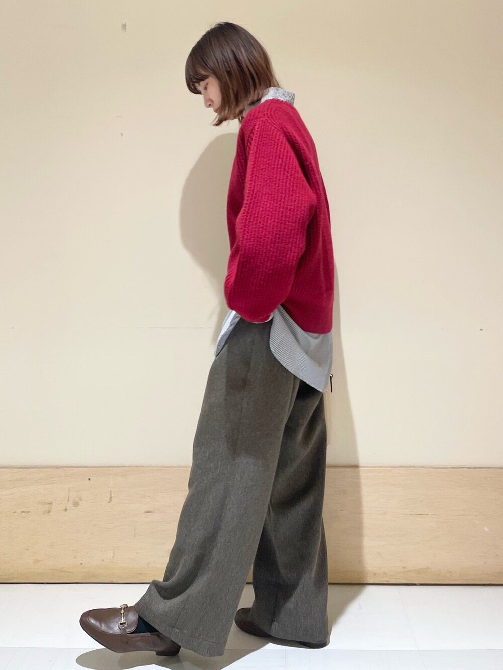 レッド系のニット/セーター、ブラウン系のその他パンツ、ブルー系のシャツ/ブラウスを着用したレディースの冬コーディネートの5枚目の写真