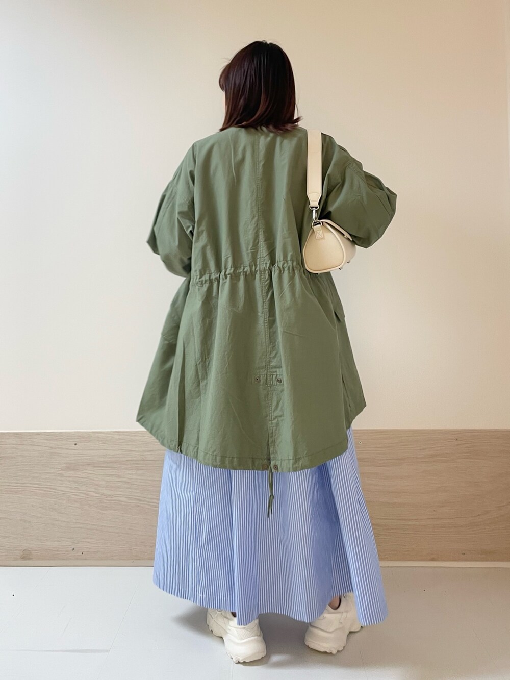 ホワイト系のショルダーバッグ、グリーン系のモッズコート、ブルー系のワンピースを着用したレディースの春コーディネートの5枚目の写真