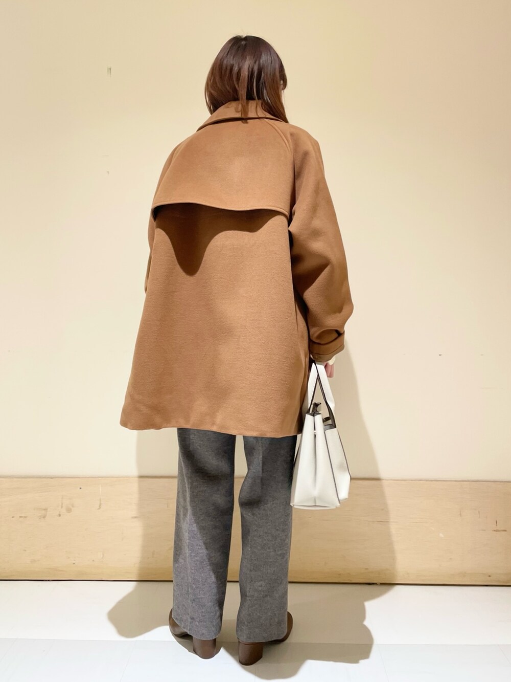イエロー系のピーコート、ホワイト系のニット/セーター、グレー系のその他パンツを着用したレディースの冬コーディネートの6枚目の写真