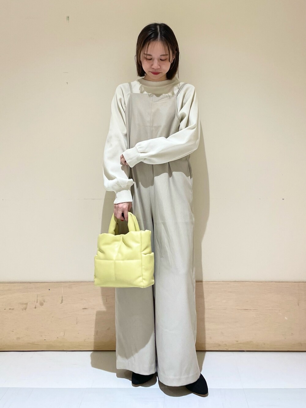 ホワイト系のニット/セーター、ベージュ系のサロペット/オーバーオール、イエロー系のトートバッグを着用したレディースの秋コーディネートの3枚目の写真