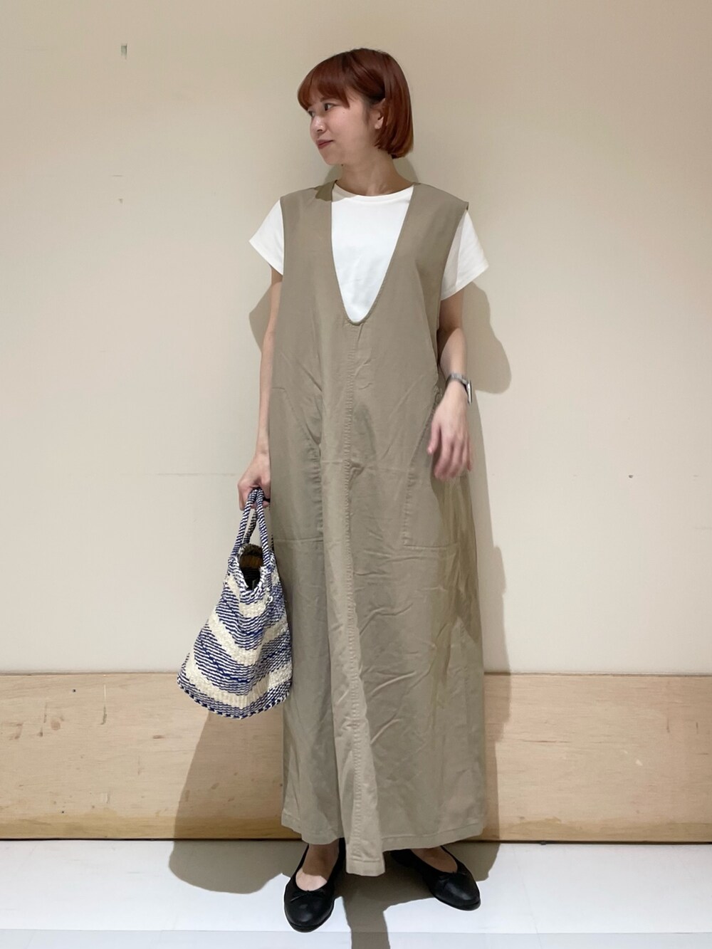 ベージュ系のワンピース、ホワイト系のTシャツ/カットソー、ブラック系のバレエシューズを着用したレディースの春コーディネートの3枚目の写真