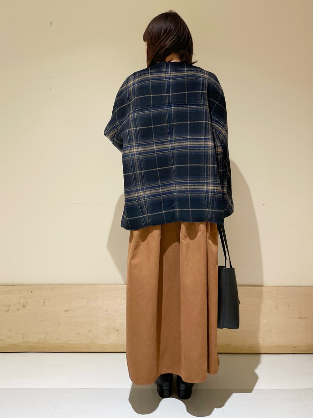 ブルー系のノーカラージャケット、イエロー系のワンピース、ブラック系のブーツを着用したレディースの冬コーディネートの3枚目の写真