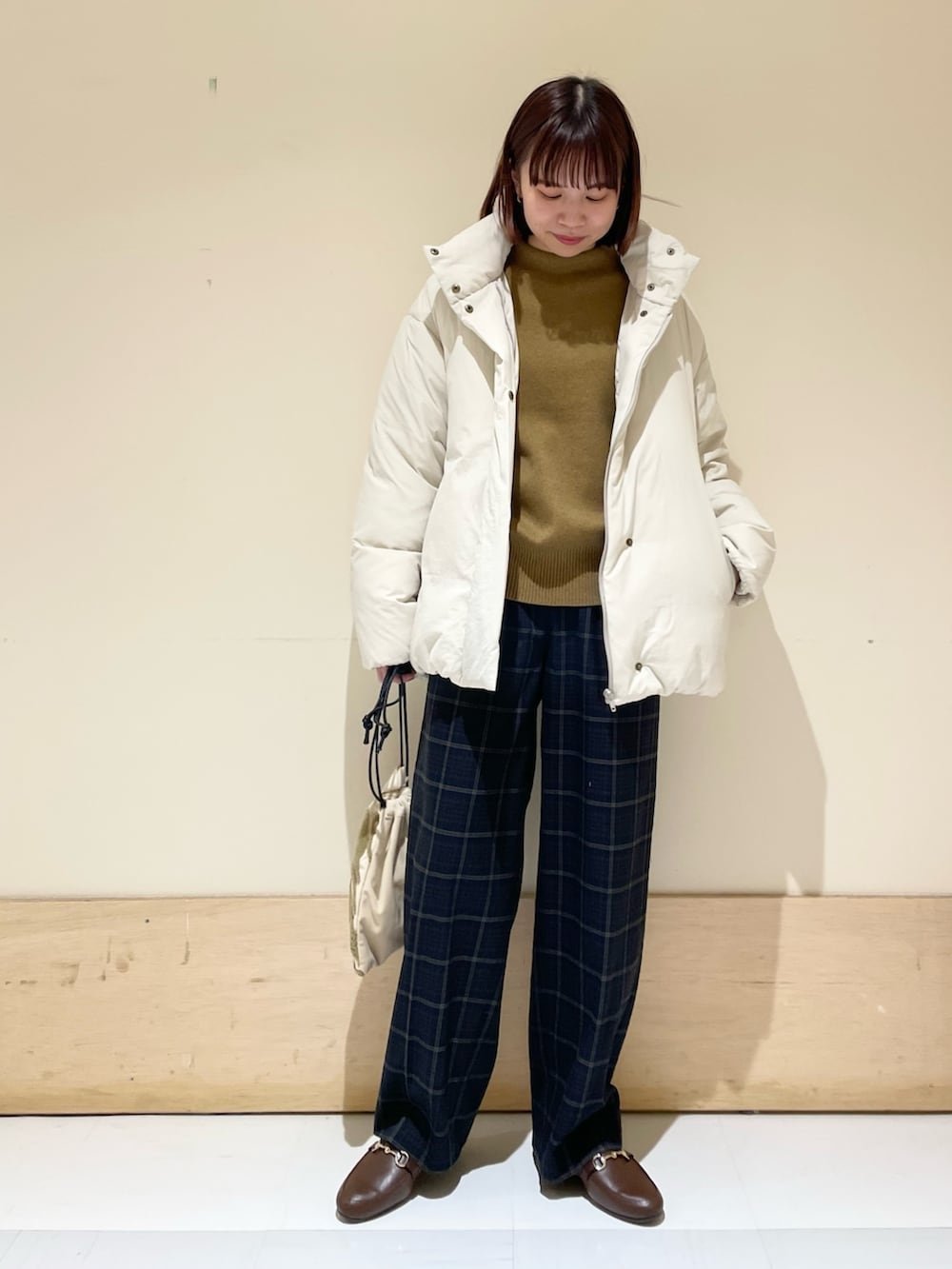 グリーン系のニット/セーター、ホワイト系のダウンジャケット/コート、ブラウン系のローファーを着用したレディースの秋コーディネートの3枚目の写真