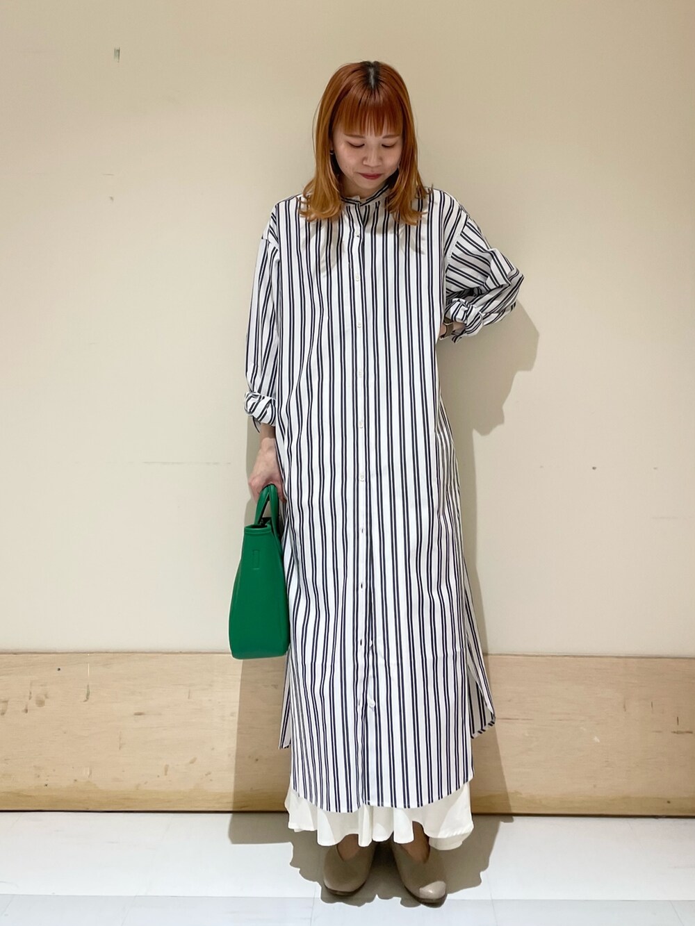 グリーン系のトートバッグ、ベージュ系のパンプス、ブルー系のワンピースを着用したレディースの春コーディネートの2枚目の写真